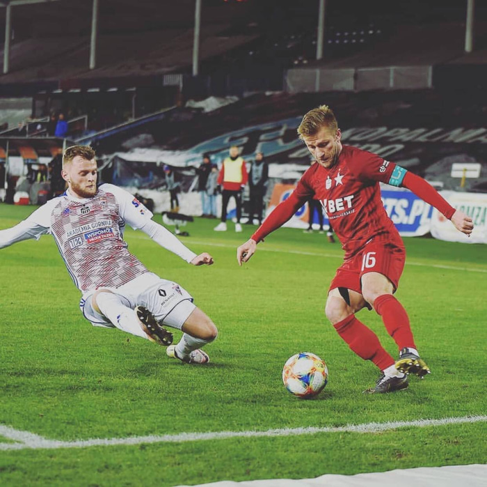 Adam Örn tæklar hér Jakub Blazcykowski, fyrrum leikmann Dortmund, í leik Gornik og Wisla Krakow.