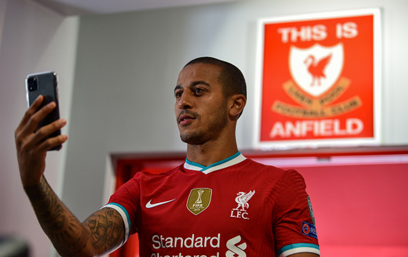 Thiago smellir af mynd í Liverpool treyjunni.