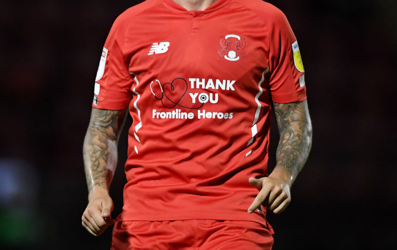 Kane á auglýsinguna framan á treyjum Leyton Orient. Þar er þakkað heilbrigðisstarfsfólki fyrir vel unnin störf á tímum Covid-19.