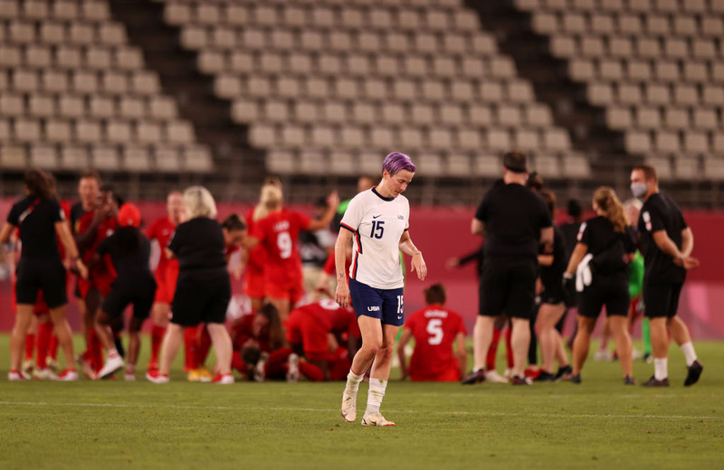 Megan Rapinoe svekkt á meðan leikmenn Kanada fagna.